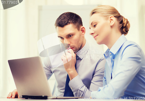 Image of serious business couple with laptop computer