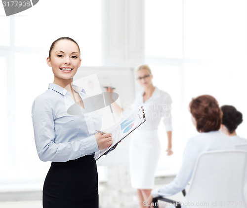 Image of young smiling businesswoman with clipboard and pen