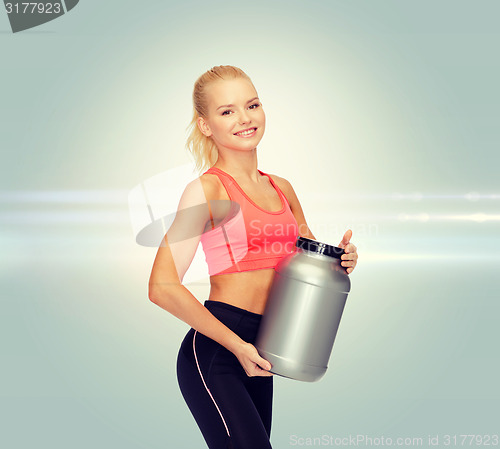 Image of smiling sporty woman with jar of protein