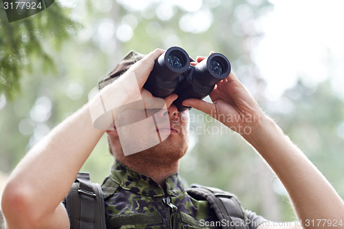 Image of young soldier or hunter with binocular in forest