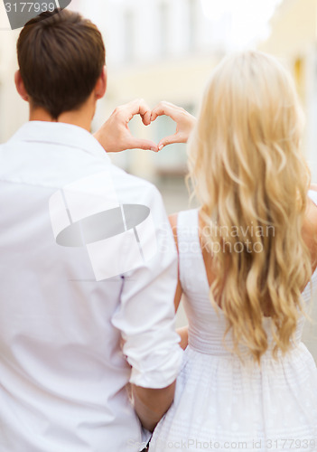 Image of romantic couple in the city making heart shape