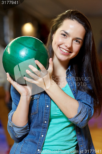 Image of happy young woman holding ball in bowling club