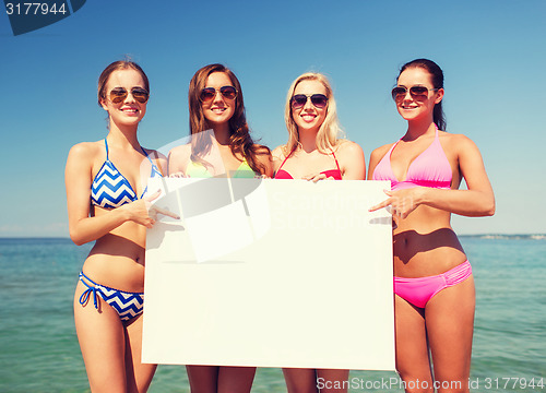 Image of group of smiling women with blank board on beach