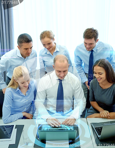 Image of smiling business people with laptop in office