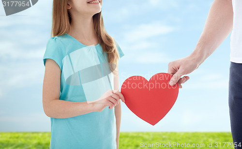 Image of close up of girl and male hand holding red heart