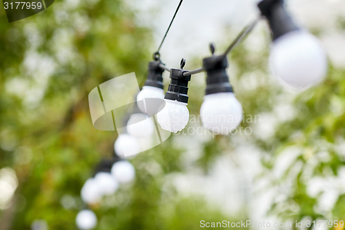 Image of close up of bulb garland hanging in rainy garden