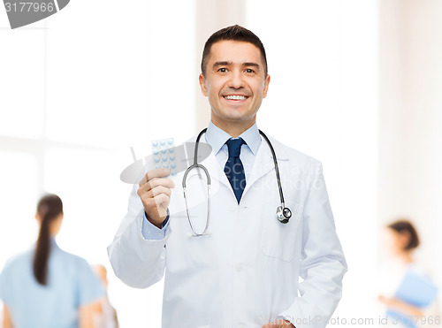 Image of smiling male doctor in white coat with tablets