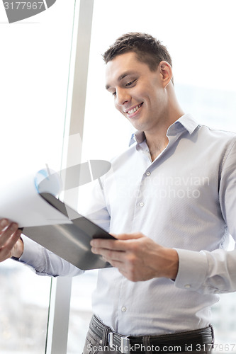 Image of smiling businessman with clipboard in office