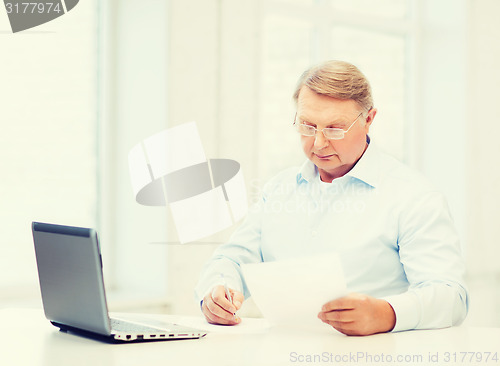 Image of old man in eyeglasses filling a form at home