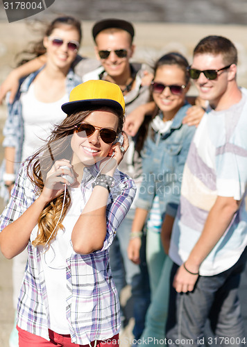 Image of teenage girl with headphones and friends outside