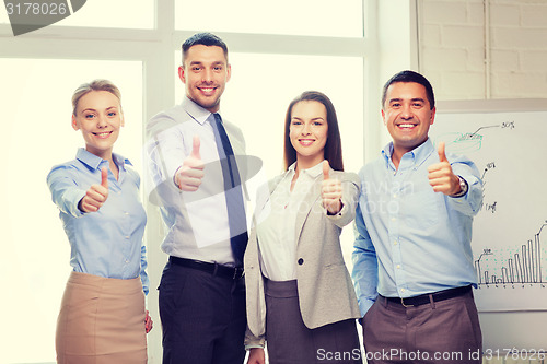 Image of business team showing thumbs up in office