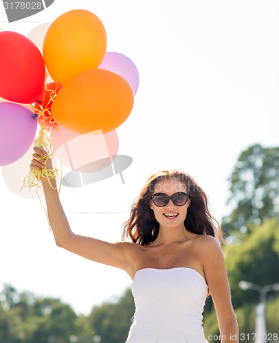 Image of smiling young woman in sunglasses with balloons