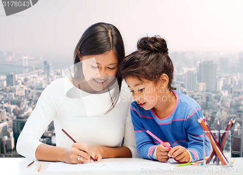 Image of happy mother and daughter drawing with pencils