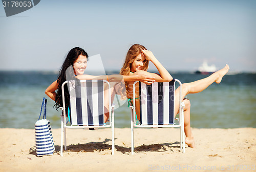 Image of girls sunbathing on the beach chairs