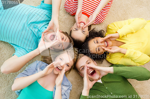 Image of smiling people lying down on floor and screaming