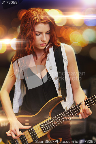 Image of red haired woman playing guitar on stage