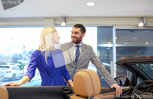 Image of happy couple buying car in auto show or salon