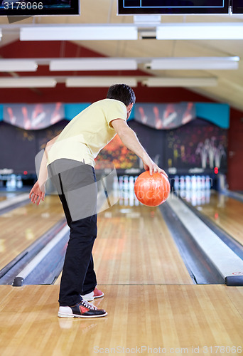 Image of happy young man throwing ball in bowling club