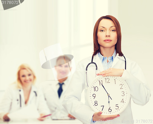 Image of calm female doctor with wall clock