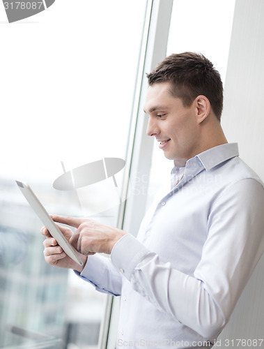 Image of smiling businessman with tablet pc in office