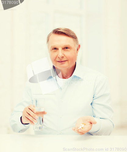 Image of old man with pills ang glass of water