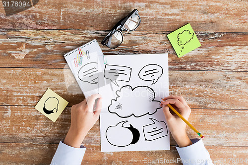 Image of close up of hands drawing text bubbles in notebook