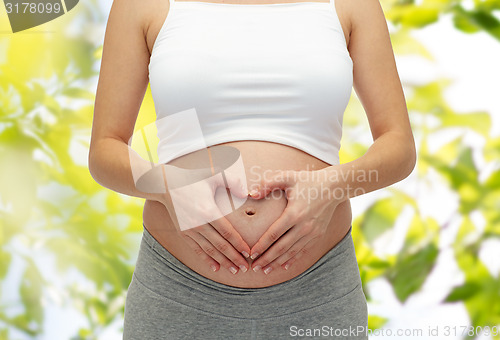 Image of close up of pregnant woman touching her bare tummy