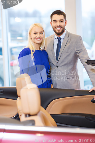 Image of happy couple buying car in auto show or salon