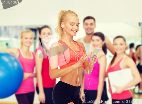 Image of smiling sporty woman with smartphone and earphones