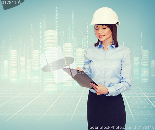 Image of smiling businesswoman in helmet with clipboard