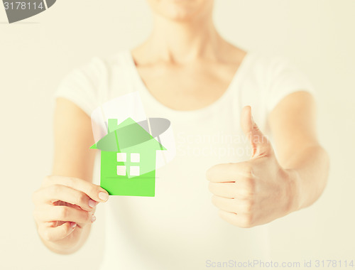 Image of woman hands holding green house