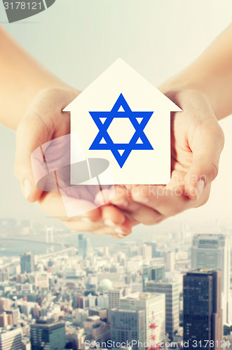 Image of close up of hands holding house with star of david