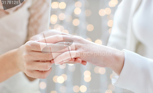 Image of close up of lesbian couple hands with wedding ring