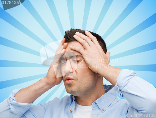 Image of unhappy man with closed eyes touching his forehead