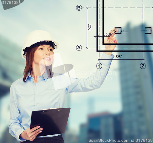 Image of smiling businesswoman in helmet with clipboard