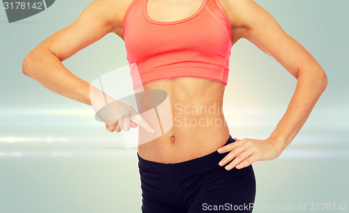 Image of close up of woman pointing finger at her six pack