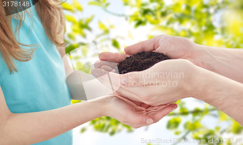 Image of close up of father and girl hands holding sprout