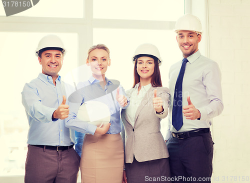 Image of happy business team in office showing thumbs up