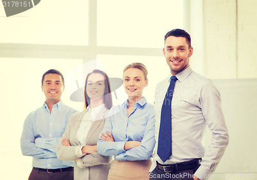 Image of smiling businessman in office with team on back