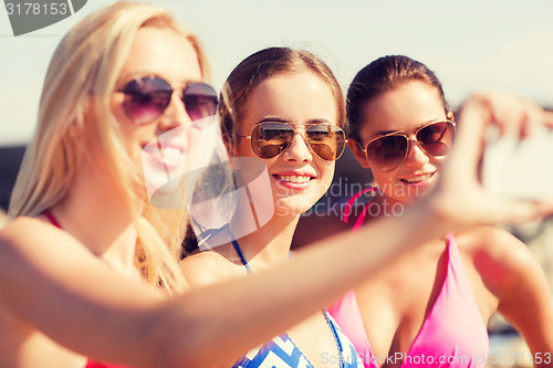 Image of group of smiling women making selfie on beach