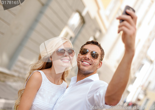 Image of smiling couple with smartphone in the city