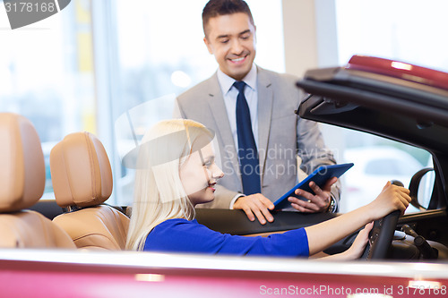 Image of happy woman with car dealer in auto show or salon