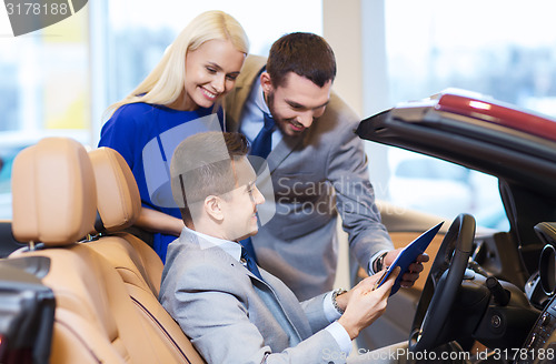 Image of happy couple with car dealer in auto show or salon