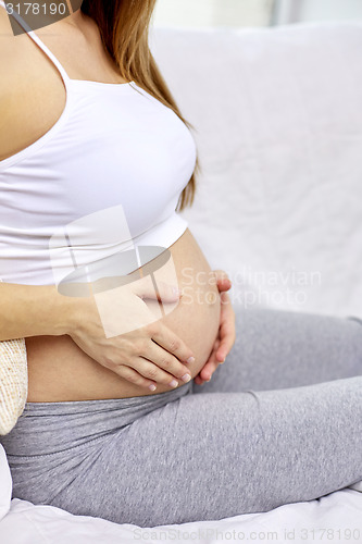 Image of close up of pregnant woman with bare tummy at home