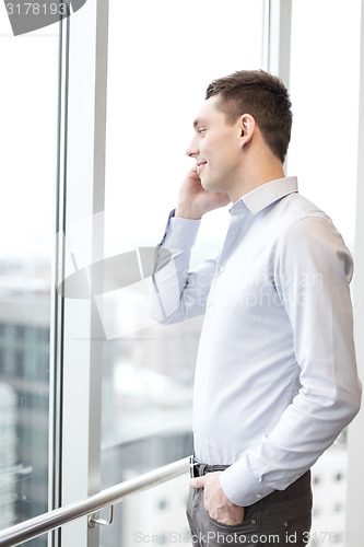 Image of smiling businessman with smartphone in office