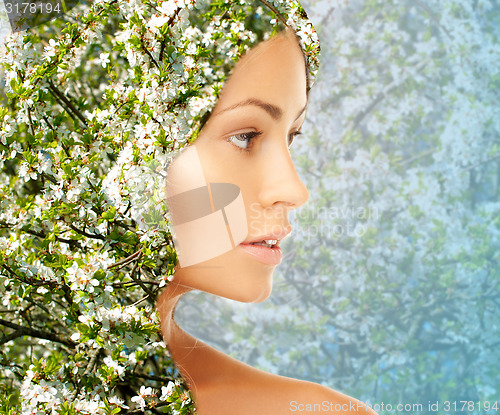 Image of young woman face over blooming tree pattern