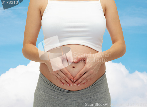 Image of close up of pregnant woman touching her bare tummy