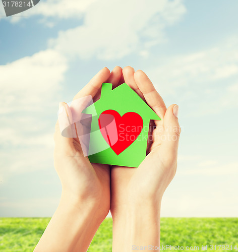 Image of hands holding green paper house