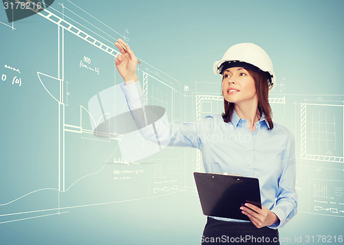 Image of smiling businesswoman in helmet with clipboard