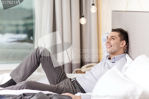 Image of happy businesswoman lying in bed in hotel room